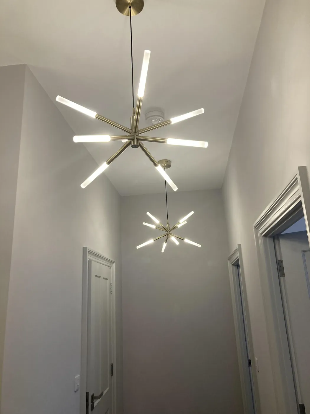 Modern starburst ceiling lights fitted in a double-height hallway