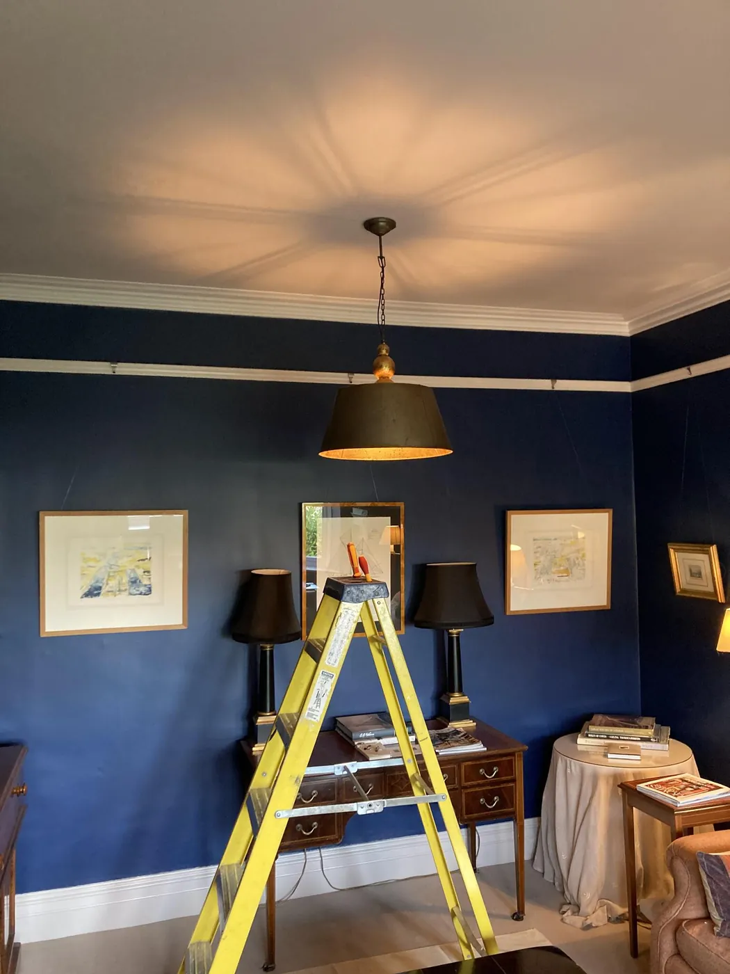 Pendant light installed above a dining table in a navy room