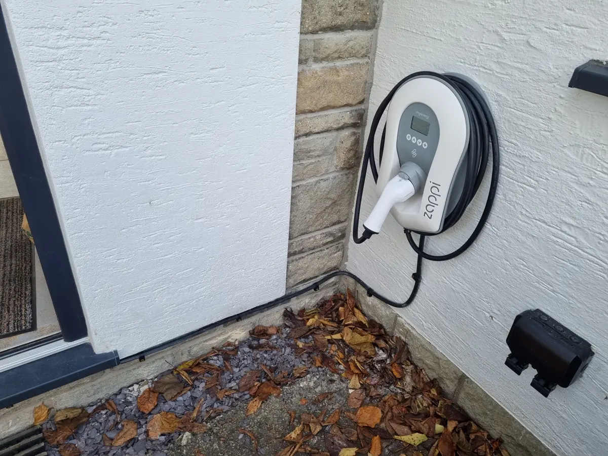 Wall-mounted EV charger installed on a rendered house wall