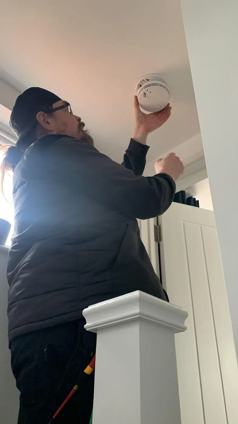 Electrician fitting a ceiling smoke alarm