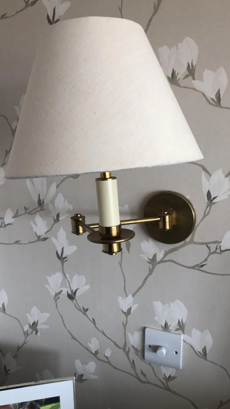 Brass wall light fitted on floral wallpaper